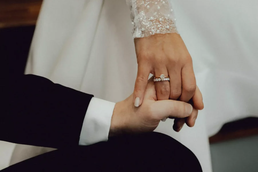 Der Bräutigam hält die Hand seiner Braut. Die Braut trägt ihren Ehe- und Verlobungsring.